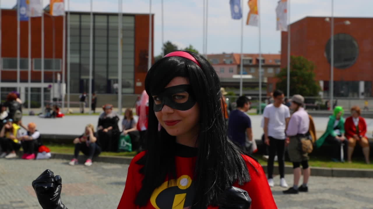 Women in black mask and her hand flex to camera in homemade comics costume in public event during a meeting of anime comics and manga lovers AnimeFest Brno expo camera in 120fps.