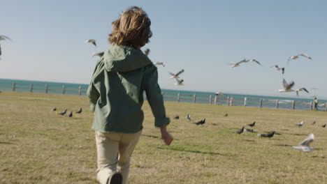 portrait of boy running enjoying chasing birds on seaside beach park lively child playing