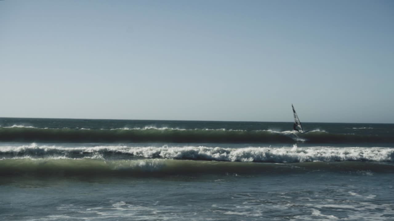 windsurfista luchando contra las olas en langebaan, ciudad del cabo