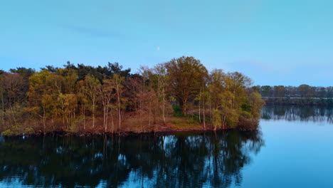 calm waters reflect trees. aerial view capturing the serene waters of a lake surrounded by lush greenery and trees in the netherlands at dusk
