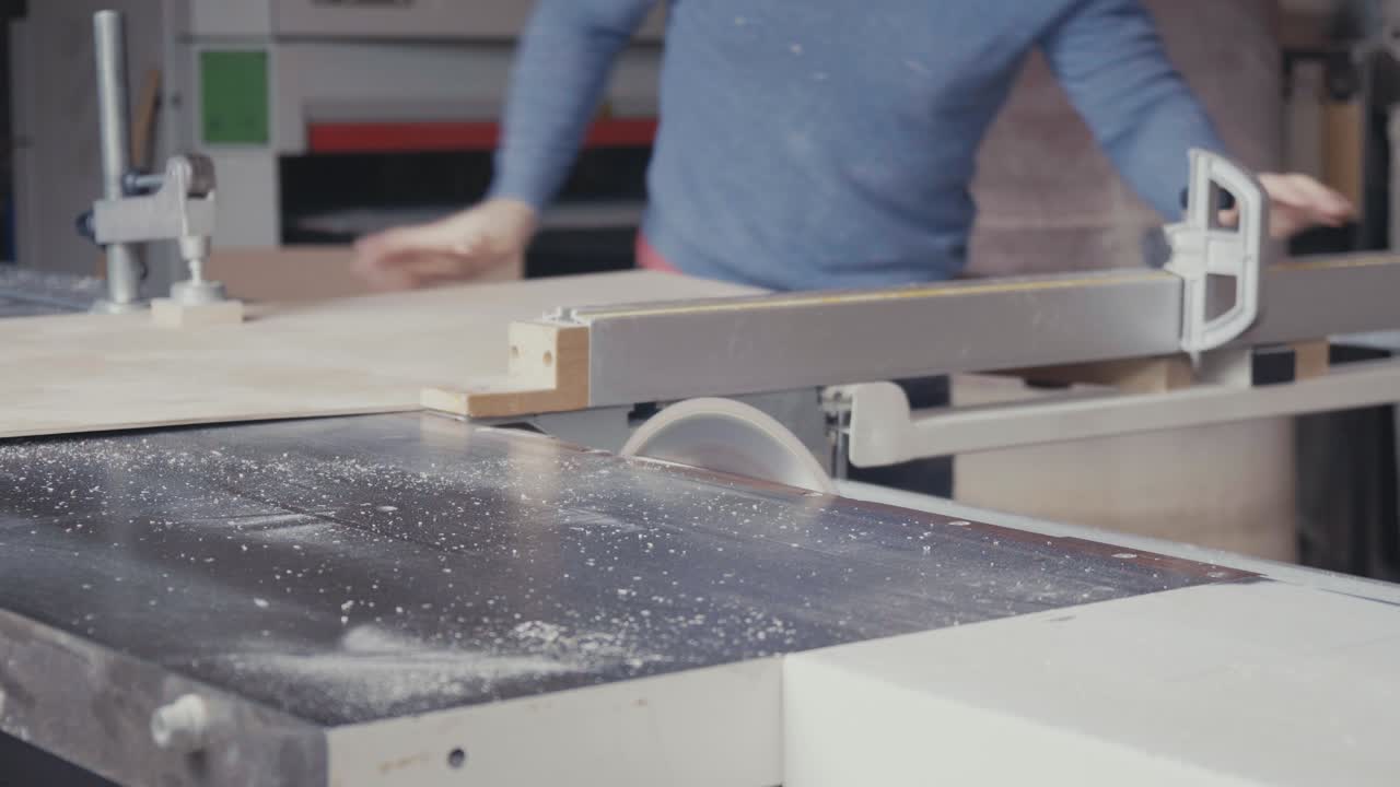 carpintero cortando una hoja de madera contrachapada con una sierra de mesa