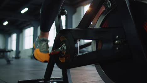 Close-up-athletic-woman-leg-spinning-exercising-workout-on-stationary-cycling-machine-bike,-indoors