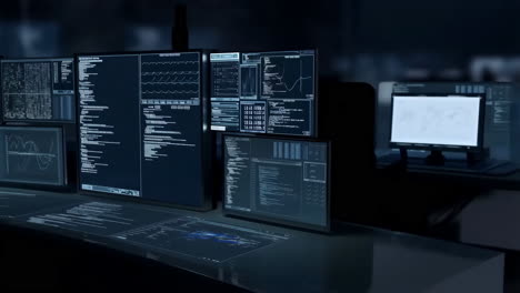 multiple computer monitors displaying complex data and code in a dark control room setting
