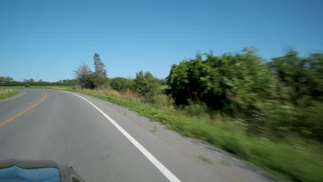 vista frontal de un automóvil en movimiento en un camino rural en el condado de prince edward
