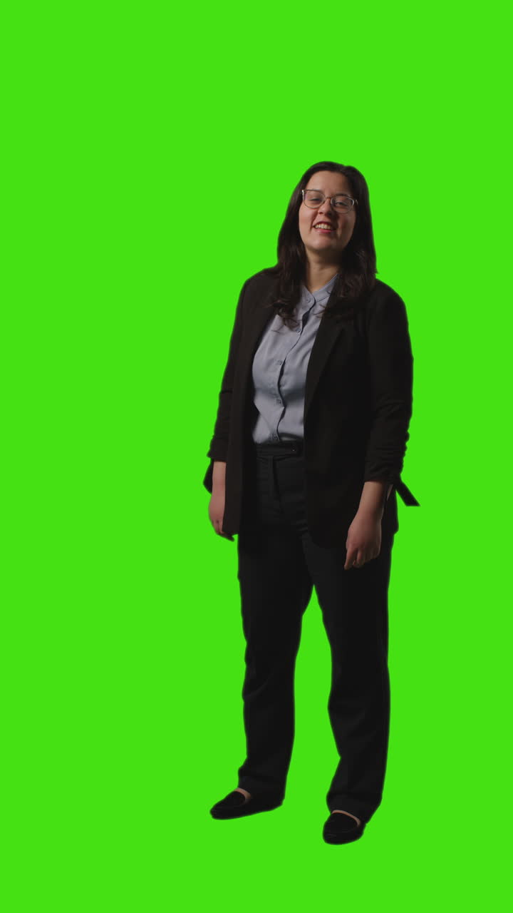 Vertical Video Full Length Shot Of Smiling Businesswoman Wearing Glasses And Suit Standing Against Green Screen