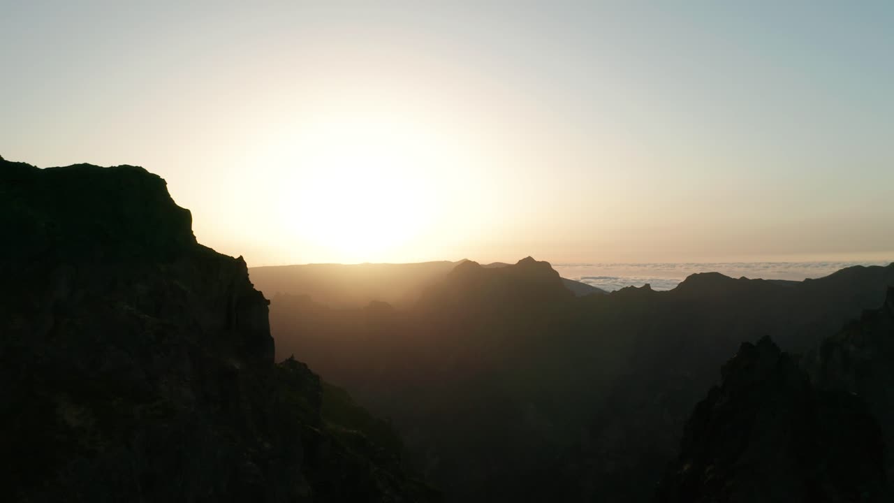 Truck right aerial of spectacular mountain range during bright golden sunset