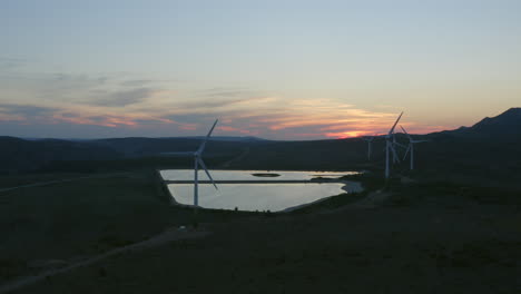 wind farm at sunset over a mountain lake