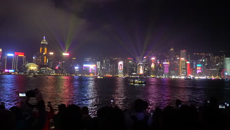 Hong-Kong-Harbour-Light-Show-Bei-Nacht-Mit-Schiff,-Das-Am-Stadtbild-Vorbeifährt