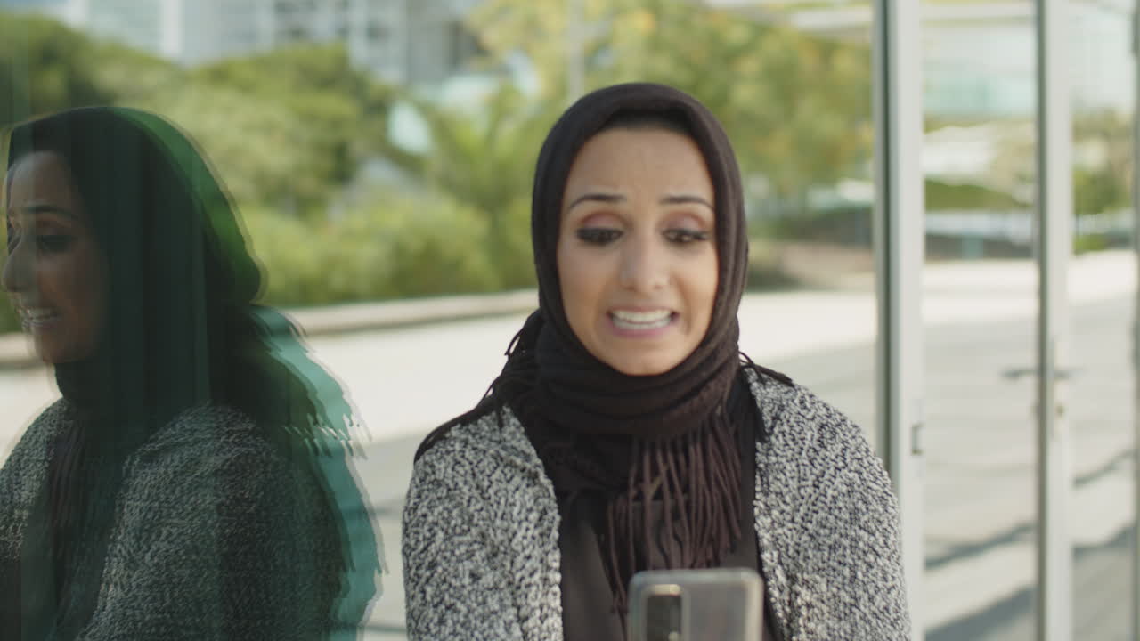 Close-up of young muslim woman having video call outdoors.