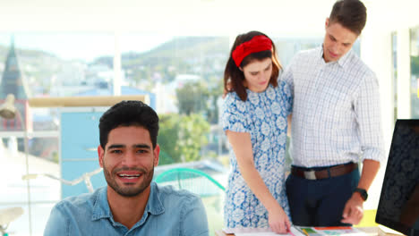 Ejecutivo-Sonriendo-Mientras-Sus-Compañeros-De-Trabajo-Trabajan-En-Segundo-Plano-En-La-Oficina-4k