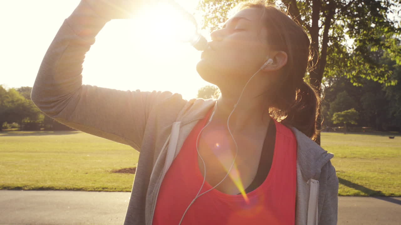 mujer de fitness bebiendo agua al aire libre en el parque
