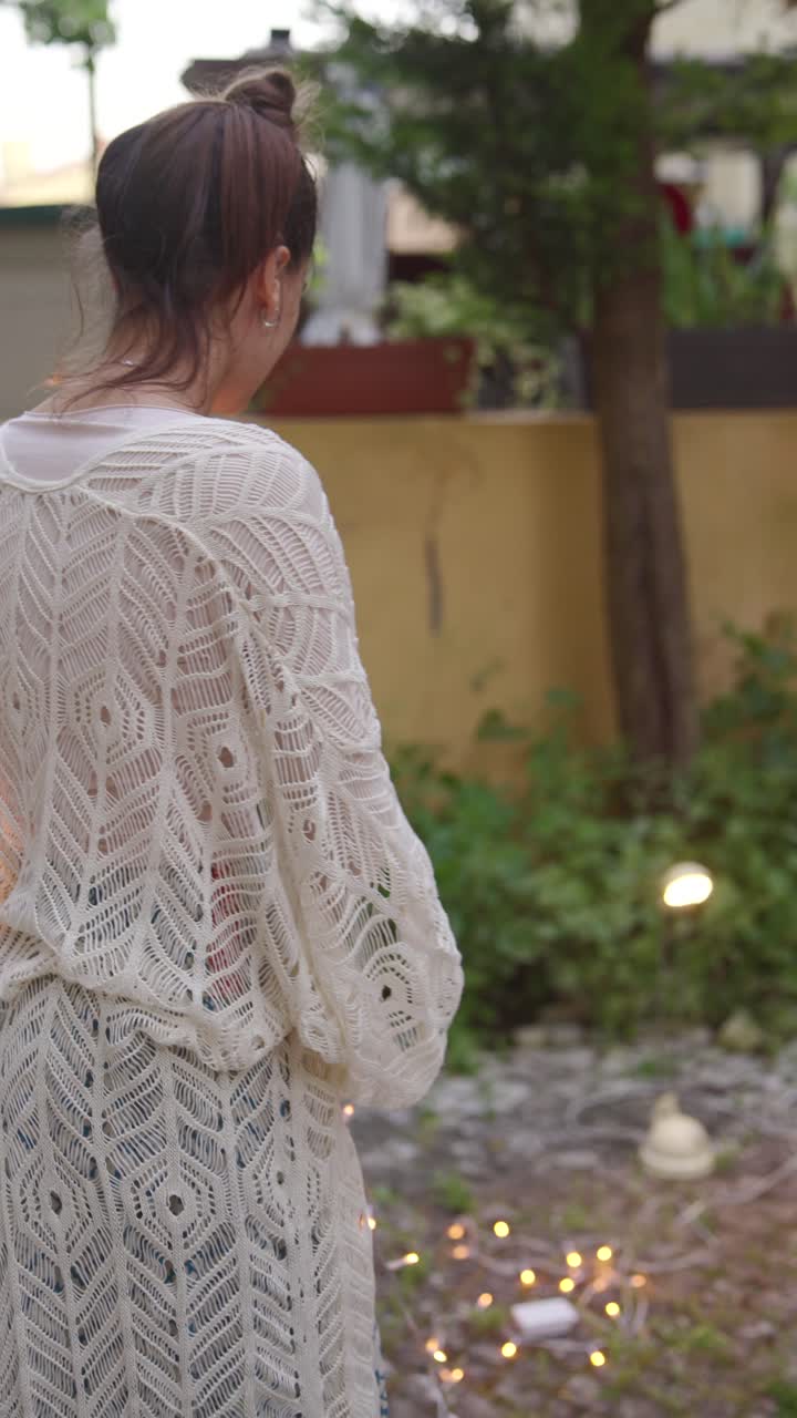 Woman in a lace cardigan in a garden at night