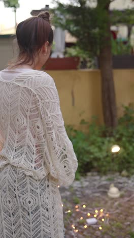 woman in a lace cardigan in a garden at night