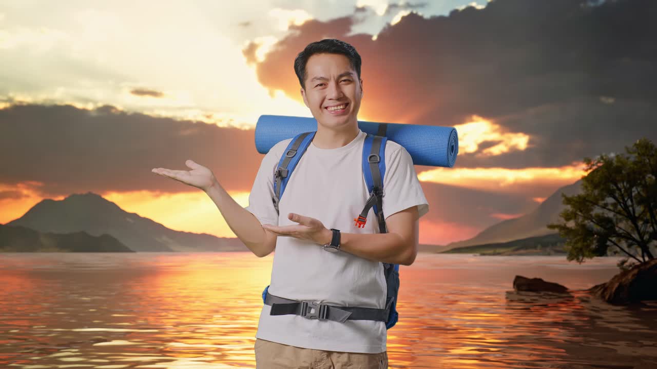 excursionista masculino asiático con mochila de montañismo sonriendo y señalando hacia un lado en un lago