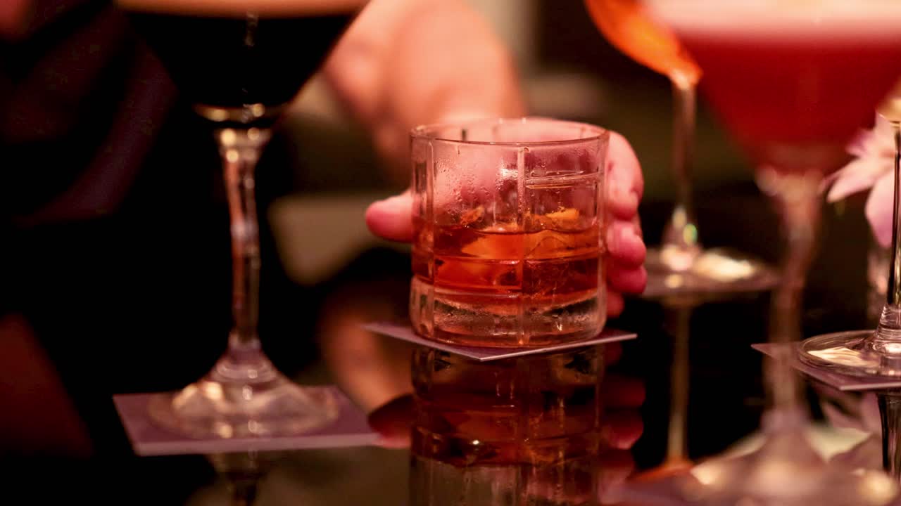 manos alcanzando bebidas en una mesa