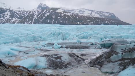 Static,-shot-of-the-sea,-at-skaftafellsjokull-turquoise-glacier,-snowy-mountains-in-the-background,-on-a-cloudy-day,-in-South-coast-of-Iceland