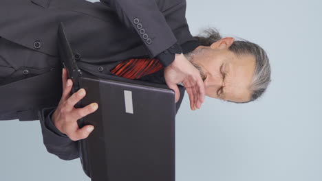 Vertical video of Tired old businessman falling asleep at laptop.