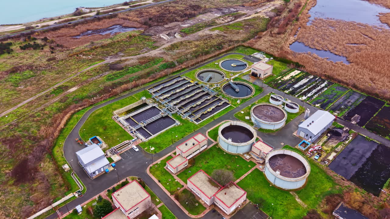 Water treatment plant with various tanks and filtration systems located near wetlands under cloudy sky