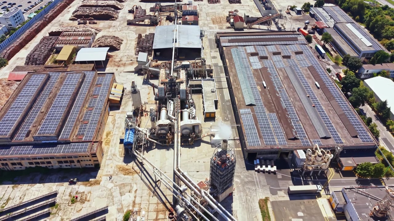 Sito industriale con magazzini e pannelli solari in una città con molti edifici nelle vicinanze