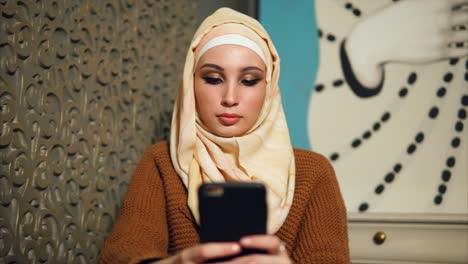 woman in hijab using smartphone in a cafe