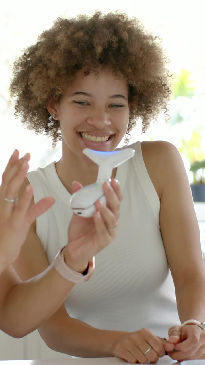 Vídeo vertical: Mostrando dispositivo, amigo movendo LED T ao longo da mulher de regata na mesa, exibindo mudança