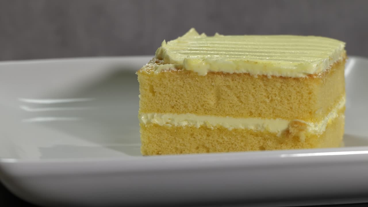 A Slice of Vanilla Cake with Frosting on a White Plate