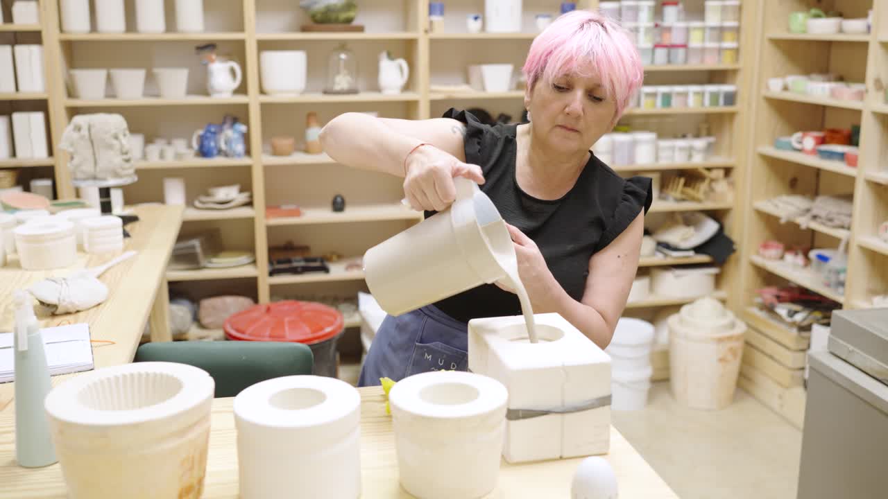 Woman pouring liquid into mold for ceramic creation