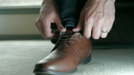 man putting on brown dress shoe