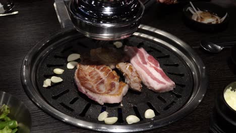 Samgyeopsal---Barbacoa-Coreana-De-Vientre-De-Cerdo-Asado-A-La-Parrilla-Con-Ajo-En-Un-Restaurante