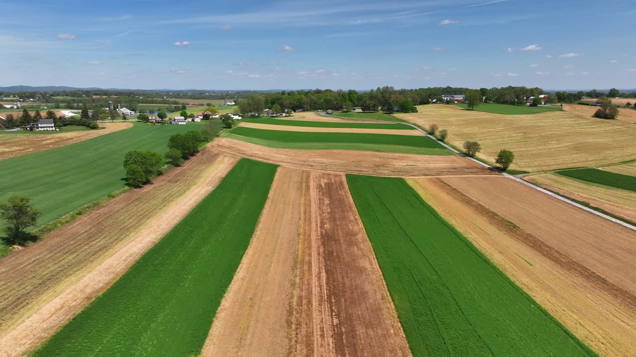 toma aérea lateral amplia de campos agrícolas en diferentes colores durante un día soleado en el campo americano