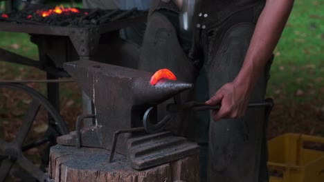 blacksmith shop, male hands with hammer forging a heart of iron