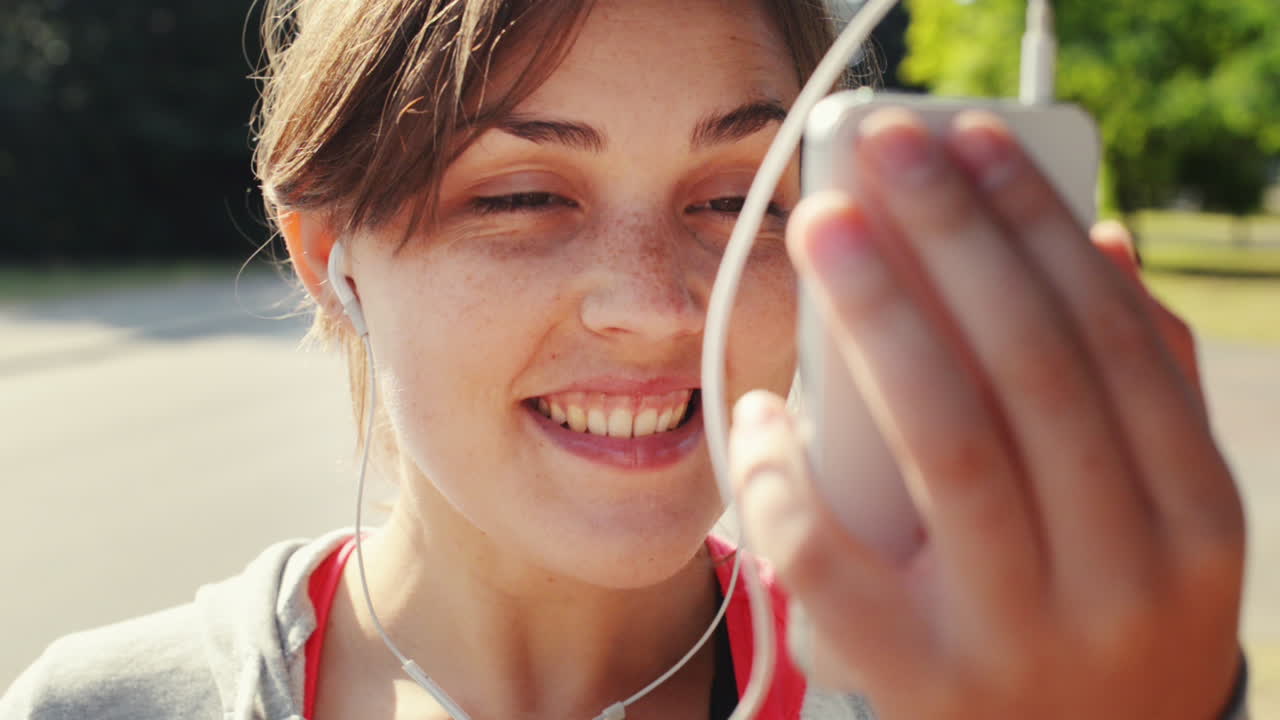 mujer enviando mensajes de video al aire libre con el uso compartido de teléfonos móviles