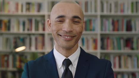 close up portrait of  bald hispanic businessman looking at camera standing library bookshelf in background