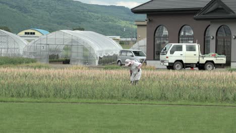 Well-Equipped-Farmer-Working-in-Field,-Static-Shot,-Mountain-Background