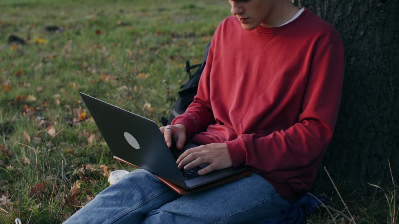 Young adult working on laptop in a park