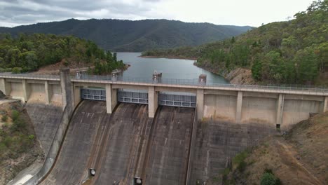 aerial descending over the spillway and behind the dam wall at lake eildon, victoria, australia