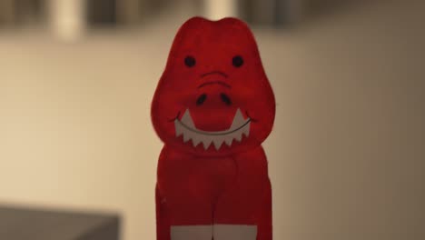 a red tyrannosaurus rex finger puppet talking to the camera