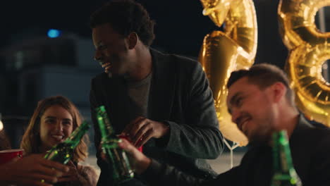 group of multiracial friends celebrating birthday party on rooftop at night drinking making toast to friendship having fun sharing celebration