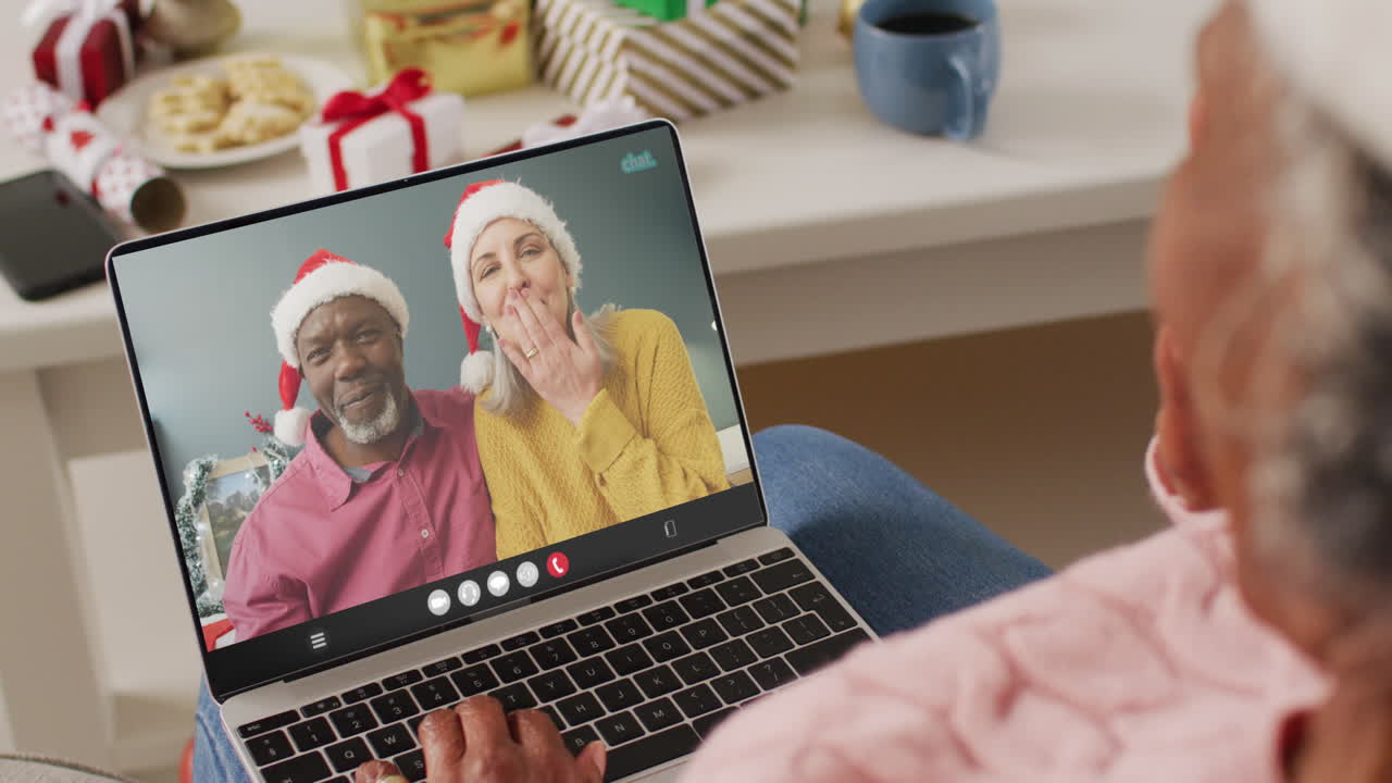 Donna anziana afroamericana che fa una videochiamata di Natale con una coppia anziana di diverse etnie