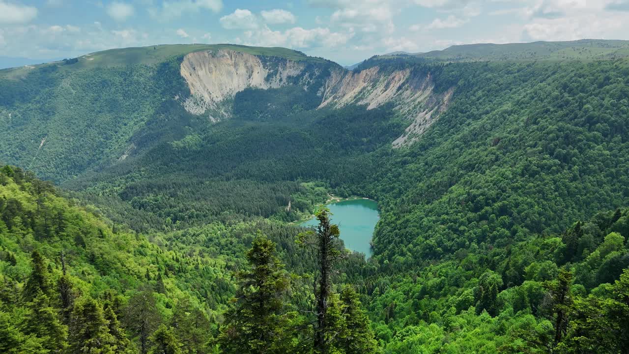 Vista panoramica di montagna con lago e foresta sotto un cielo blu