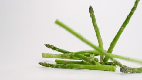 Asparagus-stalks-individually-falling-and-bouncing-on-white-backdrop-in-slow-motion-in-4k