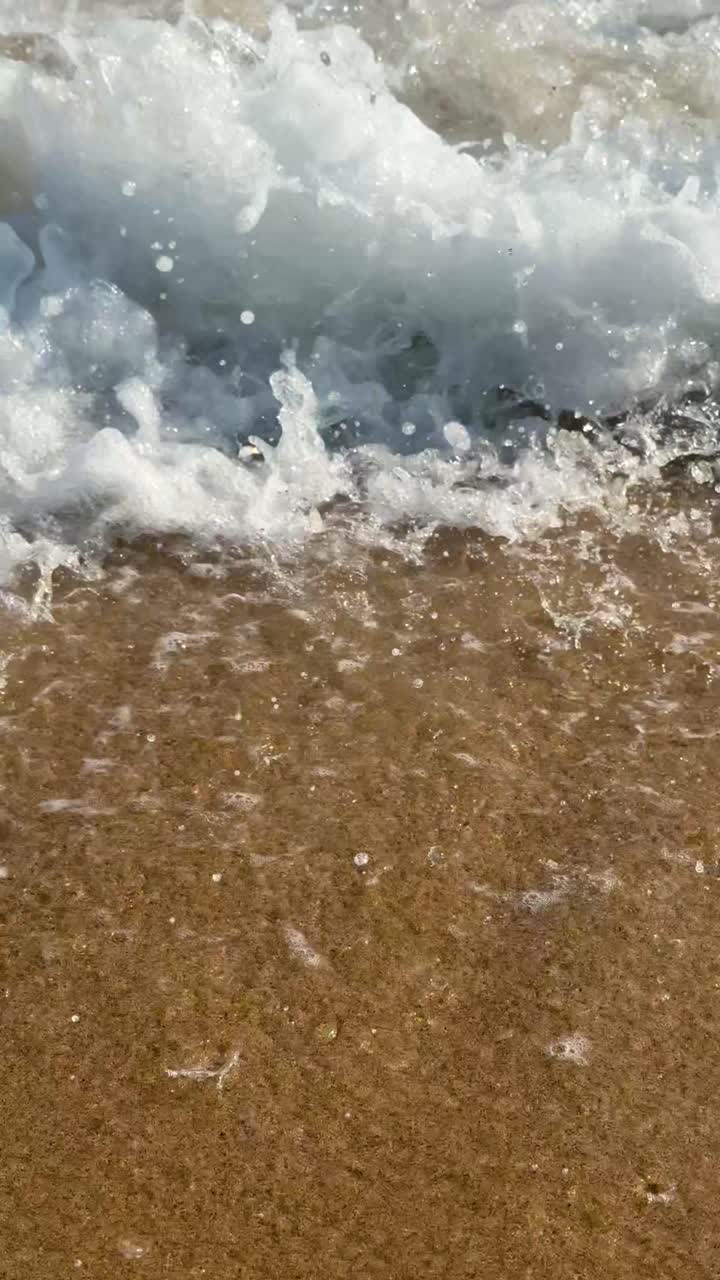 Waves lapping golden sand, sea foam in clear waters creating tranquility