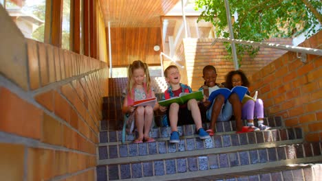 Niños-De-Escuela-Leyendo-Un-Libro-Mientras-Están-Sentados-En-Las-Escaleras-De-La-Escuela-Primaria-4k