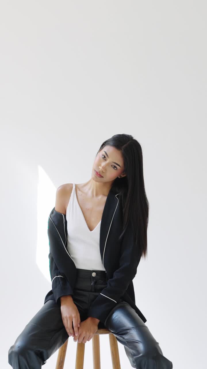 Woman in blazer and leather pants sitting on stool