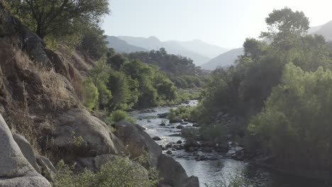 a drone starts at mountain level and raises up to reveal a beautiful stream