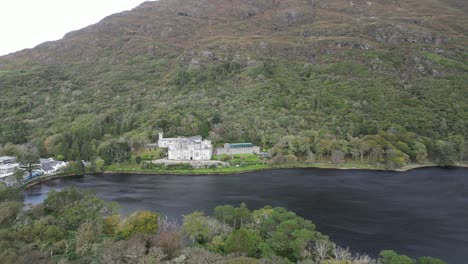 Vista-Aérea-De-La-Histórica-Y-Más-Antigua-Abadía-Benedictina,-La-Abadía-De-Kylemore-En-Connemara,-Galway,-Irlanda,-Con-Vistas-A-Un-Río-Negro-Que-Refleja-La-Abadía.