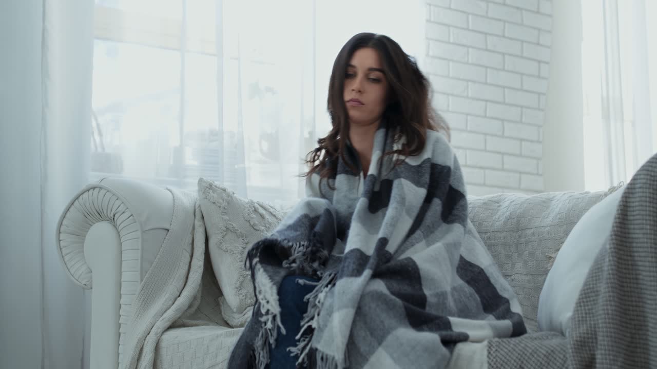 mujer envuelta en una manta en un sofá