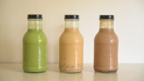 matcha green tea latte, chocolate and milk tea with pudding jelly in glass bottle on the table