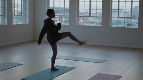 yoga-class-young-mixed-race-woman-stretching-body-on-exercise-mat-preparing-for-ealy-morning-workout-getting-ready-in-fitness-studio-at-sunrise