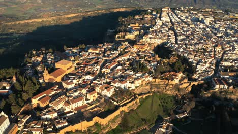 Vista-Aérea-De-Ronda,-Antigua-Ciudad-Encaramada-Sobre-Acantilados-Escarpados-Durante-La-Hora-Dorada.